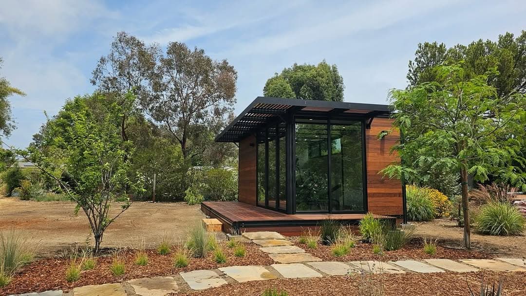 Glass and wood ADU pod with deck in landscaped yard